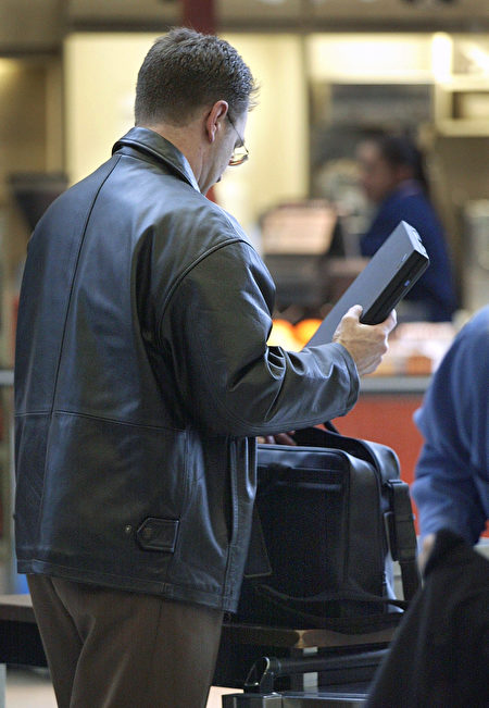 一名旅客在机场安检后将笔电放入手提行李。(Tim Boyle/Getty Images)
