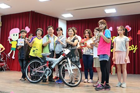 （一排左4）社区幸运女摸彩独得自行车一台，校长卢淑娟（左2）相当开心。（李撷璎／大纪元）