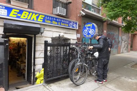 华埠E-bike电单车行的老板刘先生在检查外卖郎送来维修的自行车。