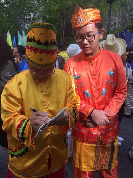 印尼大法弟子黄奕仁（左）父子在5月12日大游行前集会上。