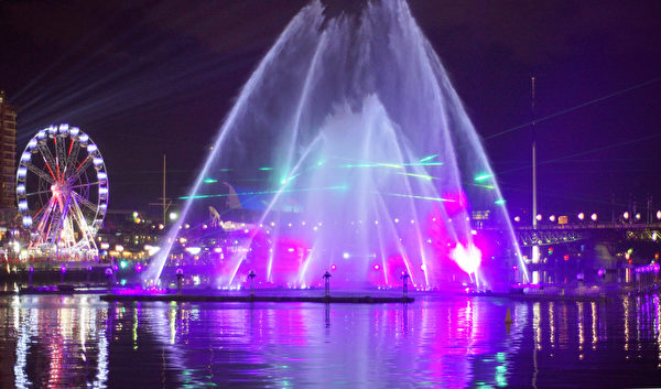 融合灯光师、作曲家、喷泉工程师和焰火设计师等合作设计出巨大喷泉水幕上，投影多样灯光图像。（周东／大纪元）