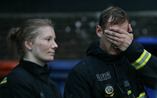 6月14日伦敦格伦菲尔塔楼发生火灾，200名消防员参与救火，图为14日当天在火灾现场的两名消防员。（DANIEL LEAL-OLIVAS/AFP/Getty Images）