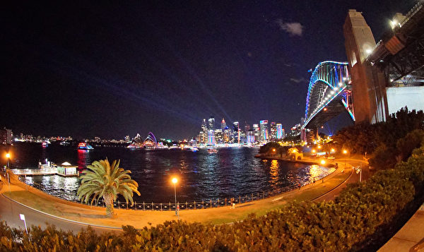 悉尼著名的海港大桥上，灯光忽明忽暗，变换着多彩颜色，与地标建筑悉尼歌剧院共同构成水上的一道风景。（周东／大纪元）