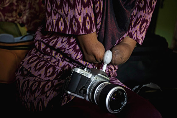 PURWOREJO, INDONESIA - MARCH 13: Armless professional photographer Rusidah, 44, carries out camera maintenance on March 13, 2012 in Purworejo, Indonesia. Rusidah shoots weddings and parties and has a small studio at home in the village of Botorejo, Bayan District, Purworejo, Central Java where her husband and son also reside. She has been in the photography business for nearly 20 years. (Photo by Ulet Ifansasti/Getty Images)