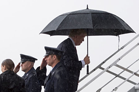 TOPSHOT - US President Donald Trump (3rd R) boards Air Force One under heavy rain at Andrews Air Force Base, Maryland, April 6, 2017. Donald Trump will host Chinese President Xi Jinping at his sun-kissed Mar-a-Lago resort in Florida on Thursday, a high-stakes first summit replete with pitfalls for both leaders. The stage is set for a carefully choreographed dinners with family and displays of bonhomie, but beneath the facade runs a wary, almost palpable, anxiety -- as the men face a make or break moment. / AFP PHOTO / JIM WATSON (Photo credit should read JIM WATSON/AFP/Getty Images)