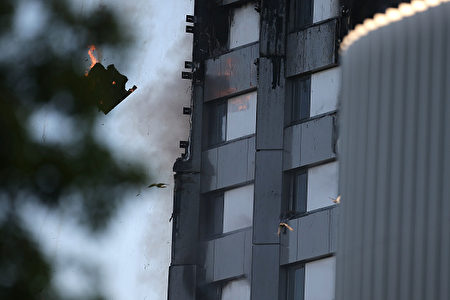 TOPSHOT - An arm holding a cloth can be seen waving from a window of Grenfell Tower as a piece of burning debris falls on June 14, 2017 in west London. The massive fire ripped through the 27-storey apartment block in west London in the early hours of Wednesday, trapping residents inside as 200 firefighters battled the blaze. Police and fire services attempted to evacuate the concrete block and said "a number of people are being treated for a range of injuries", including at least two for smoke inhalation. / AFP PHOTO / Daniel LEAL-OLIVAS (Photo credit should read DANIEL LEAL-OLIVAS/AFP/Getty Images)