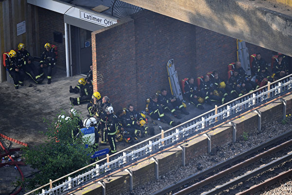 6月14日凌晨，倫敦24層的住宅樓格倫費爾塔樓陷入一片火海之中，超過200名消防員到現場滅火救人。圖為當天白天精疲力盡的消防員在塔樓附近休息，等待著進入大樓開展下一輪的救人行動。 （Leon Neal / Getty Images）