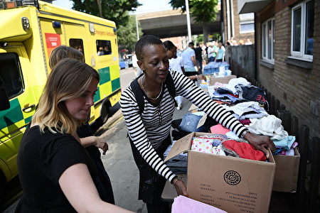 LONDON, ENGLAND - JUNE 14: Women donate clothes to a stall which has been set up to help people near the burning 24 storey residential Grenfell Tower block in Latimer Road, West London on June 14, 2017 in London, England. The Mayor of London, Sadiq Khan, has declared the fire a major incident as more than 200 firefighters are still tackling the blaze while at least 50 people are receiving hospital treatment. (Photo by Carl Court/Getty Images)