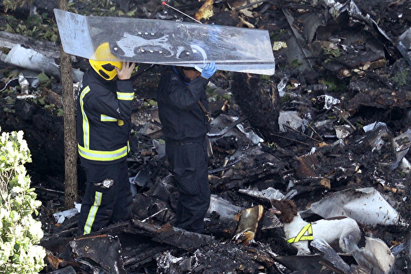 消防員和嗅探犬於2017年6月15日在倫敦格倫費爾大樓腳下檢查碎片，頭頂鋼化玻璃板，以防從上面掉下東西被砸到。14日凌晨，24層的住宅樓格倫費爾大樓被火焰吞沒，79人死亡。 (Dan Kitwood / Getty Images)
