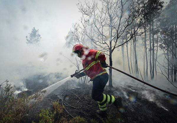 TOPSHOT - A firefighter uses a hose to combat a wildfire in Vale da Ponte, Pedrograo Grande, on June 20, 2017. The huge forest fire that erupted on June 17, 2017 in central Portugal killed at least 64 people and injured 135 more, with many trapped in their cars by the flames. / AFP PHOTO / MIGUEL RIOPA (Photo credit should read MIGUEL RIOPA/AFP/Getty Images)