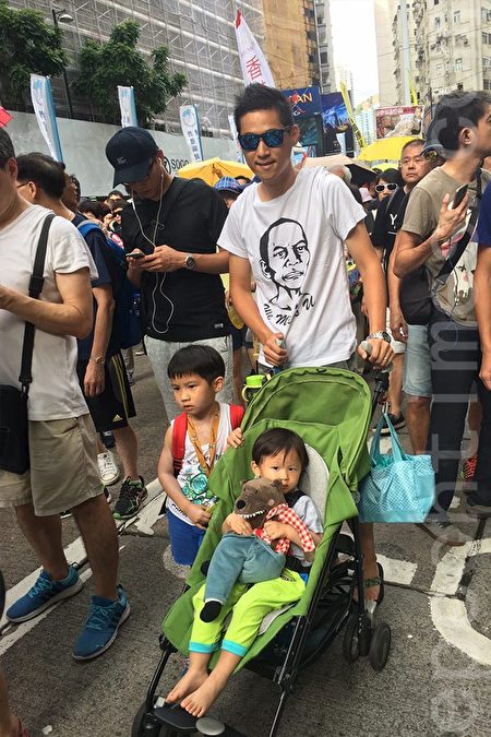 从事工程行业的黎先生夫妇带同2岁和6岁孩子上街，大的背着小背囊，小的还坐着婴儿车。（黄瑞秋／大纪元）