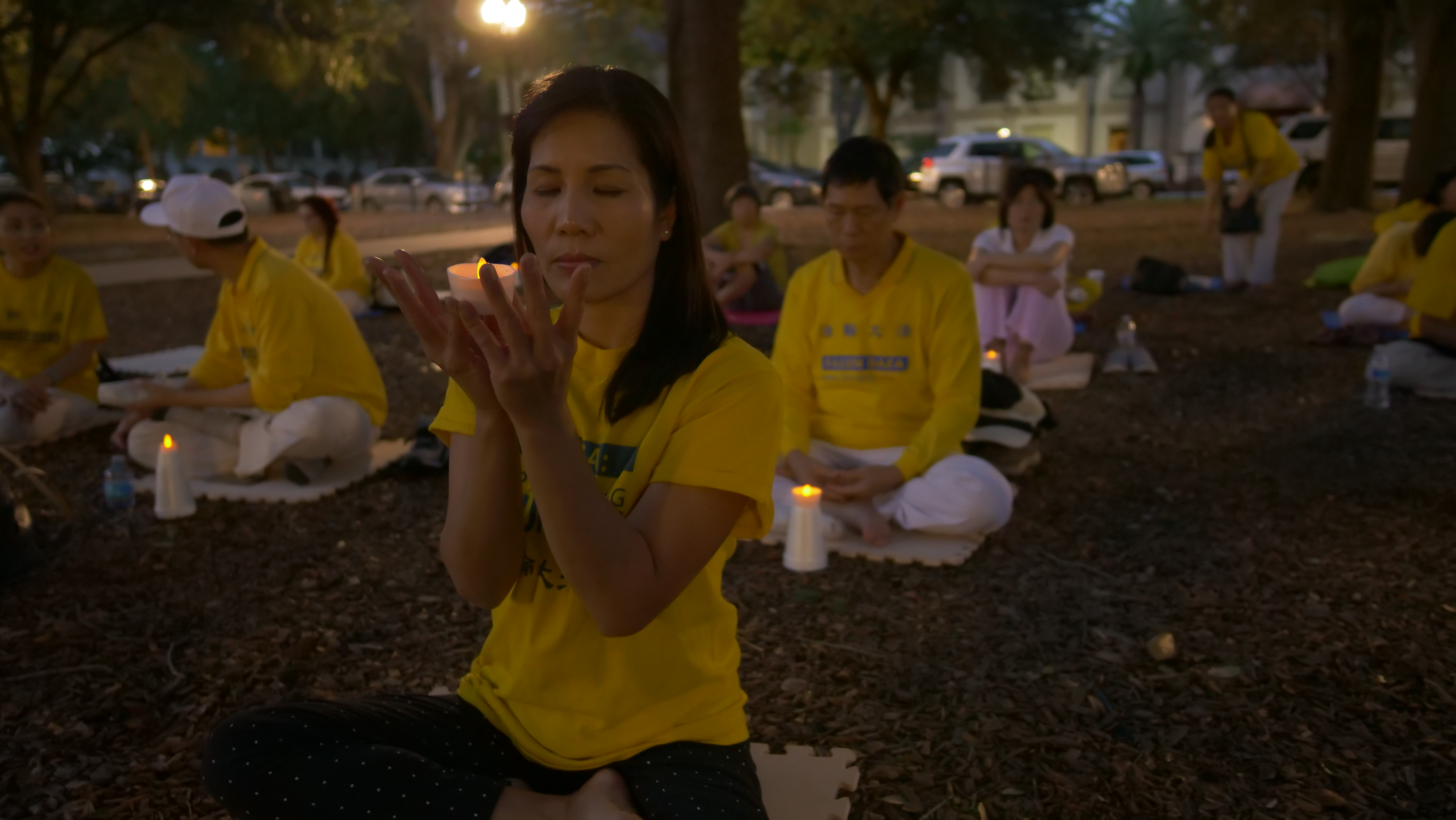 法輪功學員們盤腿打坐,手捧燭台,悼念被中共迫害致死、致殘的無數法輪功學員。 ( 岑華穎/大紀元)