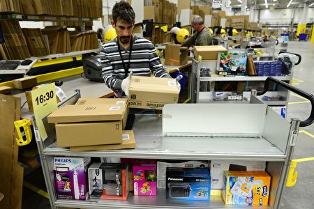 亚马逊的一家配送中心内，工人在包装和整理货品。 (JOHN MACDOUGALL/AFP/Getty Images)