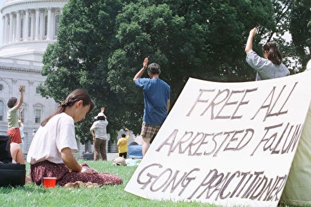 1999年7月27日，部分美国法轮功学员在国会前炼功，手写标语“释放所有被捕法轮功学员”。(Alex Wong/Getty Images)