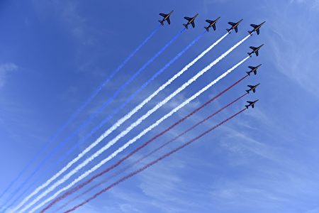 法国巡逻兵飞行表演队（Patrouille de France）的9架阿尔法教练机（Alpha Jet）飞越协和广场阅兵主席台上空，尾部喷洒出蓝白红法国国旗三色烟雾。（SAUL LOEB/AFP/Getty Images)