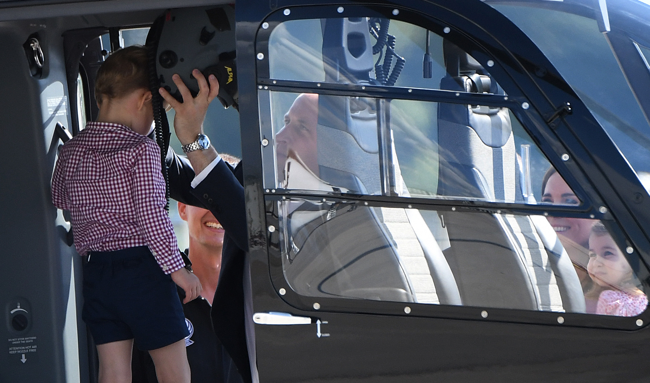 2017年7月21日，英国威廉王子携妻子与一对子女在德国汉堡参观一架直升机，威廉王子帮即将满4岁的乔治王子戴上头盔。（PATRIK STOLLARZ/AFP/Getty Images）