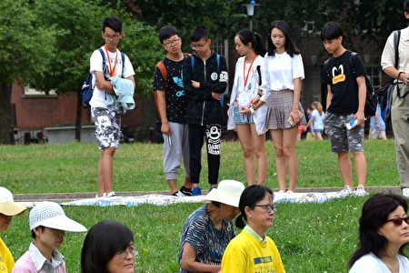 来美国暑期旅游的中国学生观看展板与炼功。（良克霖/大纪元）