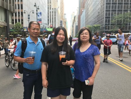 華人一家三口在東42街前往東河岸邊觀賞國慶煙花秀。