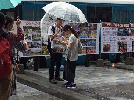 日本法輪功學員8月15日，在東京九段下車站擺真相看板，向人民講真相，並徵集聯署舉報江澤民的簽名，儘管當天遇到大雨，依然有上千名的日本民眾和外國遊客在聯署舉報書上簽了名。（英傑／大紀元）