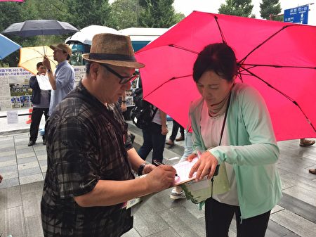 日本法輪功學員8月15日，在東京九段下車站擺真相看板，向人民講真相，並徵集聯署舉報江澤民的簽名，儘管當天遇到傾盆大雨，依然有上千名的日本民眾和外國遊客在聯署舉報書上簽了名。（英傑／大紀元）