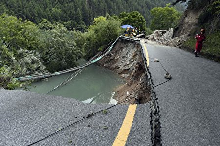 A rescuer walks past a damaged section of road in Jiuzhaigou, two days after a 6.5-magnitude earthquake hit southwest China's Sichuan province, on August 10, 2017. China on August 10 ramped up its response to an earthquake that killed 20 people and injured hundreds, sending supplies and personnel into the mountainous zone as rescuers fanned out to search for more victims. / AFP PHOTO / STR / China OUT (Photo credit should read STR/AFP/Getty Images)