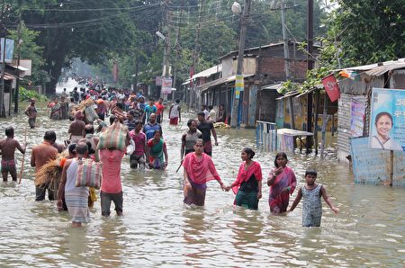 TOPSHOT - Indian residents wade through flood waters in Balurghat in West Bengal on August 17, 2017. At least 221 people have died and more than 1.5 million have been displaced by monsoon flooding across India, Nepal and Bangladesh, officials said August 15, as rescuers scoured submerged villages for the missing. / AFP PHOTO / STR (Photo credit should read STR/AFP/Getty Images)
