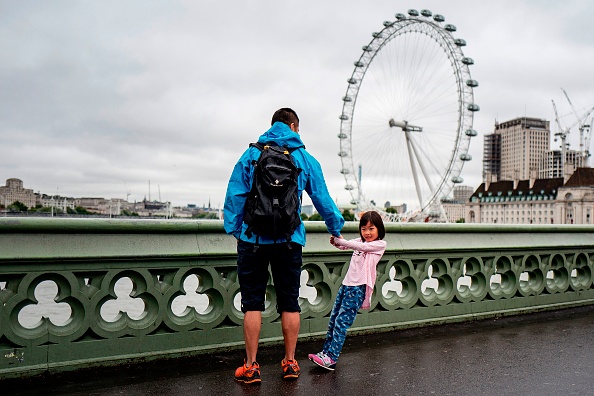 “爸爸，我要坐摩天轮！”英镑贬值，大量游客来英国旅游。今年第二季度，来英的游客人数达到大约1,075万，为有纪录以来人数最高的一个季度。图为一名儿童游客和她的爸爸站在伦敦的威斯敏斯特大桥上。(TOLGA AKMEN/AFP/Getty Images)