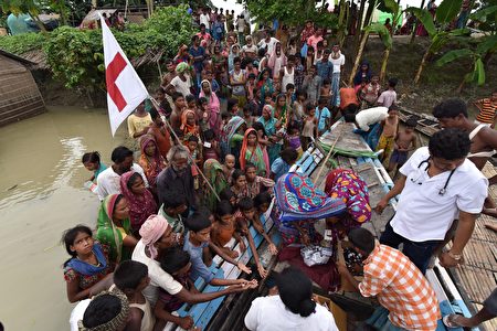 TOPSHOT - Indian medical officials of the Jhargaon Public Health Centre (PHC) distribute medicine to villagers in the flood affected Sagolikota area of Morigaon district, in India's northeastern Assam state, on August 18, 2017. At least 221 people have died and more than 1.5 million have been displaced by monsoon flooding across India, Nepal and Bangladesh, officials said August 15, as rescuers scoured submerged villages for the missing. / AFP PHOTO / Biju BORO (Photo credit should read BIJU BORO/AFP/Getty Images)