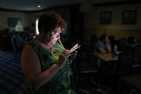 CORPUS CHRISTI, TX - AUGUST 25: Amy Currin watches the weather news on her cell phone after the power went out at the TownePlace Suites hotel where she was taking shelter from Hurricane Harvey at a place she felt was safer than her home on August 25, 2017 in Corpus Christi, Texas. Hurricane Harvey has intensified into a hurricane and is aiming for the Texas coast with the potential for up to 3 feet of rain and 125 mph winds. (Photo by Joe Raedle/Getty Images)