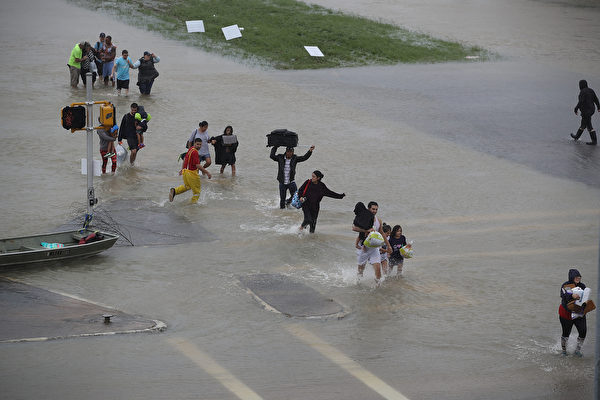 HOUSTON, TX - AUGUST 28: People walk down a flooded street as they evacuate their homes after the area was inundated with flooding from Hurricane Harvey on August 28, 2017 in Houston, Texas. Harvey, which made landfall north of Corpus Christi late Friday evening, is expected to dump upwards to 40 inches of rain in Texas over the next couple of days. (Photo by Joe Raedle/Getty Images)