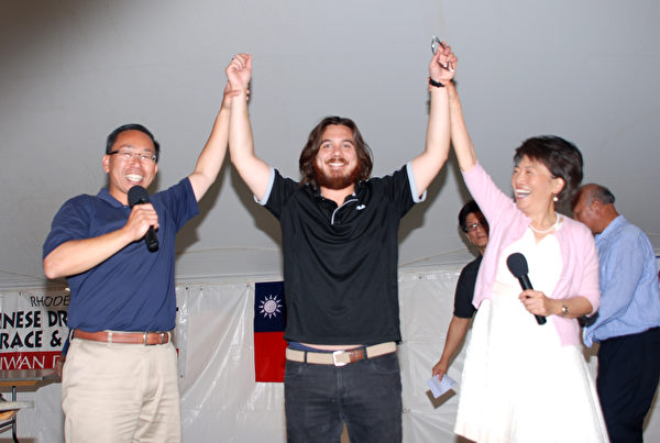 三次获吃饺子大赛冠军的 Eric Steinberg(中)和冯伟杰市长(左)、主持人胡少娟一起举臂庆祝。(王尚德/大纪元)