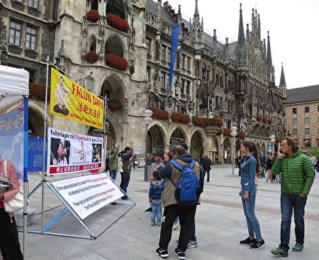 二零一七年九月二日，法輪功學員在德國慕尼黑的瑪琳廣場（Marienplatz）舉辦講真相活動，不少過往民眾駐足了解真相，並簽名譴責中共活摘法輪功學員器官。（明慧網） 