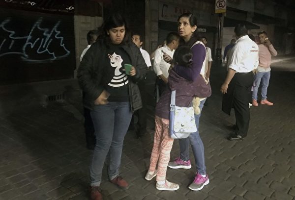 People walk along a street in downtown Mexico City during an earthquake, on September 7, 2017. An earthquake of magnitude 8.0 struck southern Mexico late Thursday and was felt as far away as Mexico City, the US Geological Survey said, issuing a tsunami warning. It hit offshore 120 kilometers (75 miles) southwest of the town of Tres Picos in the state of Chiapas. / AFP PHOTO / ALFREDO ESTRELLA