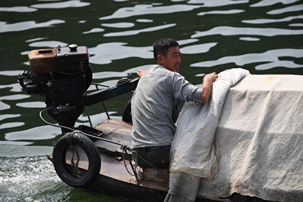 一艘朝鲜渔船靠上中国游船兜售商品。（AFP PHOTO / GREG BAKER）
