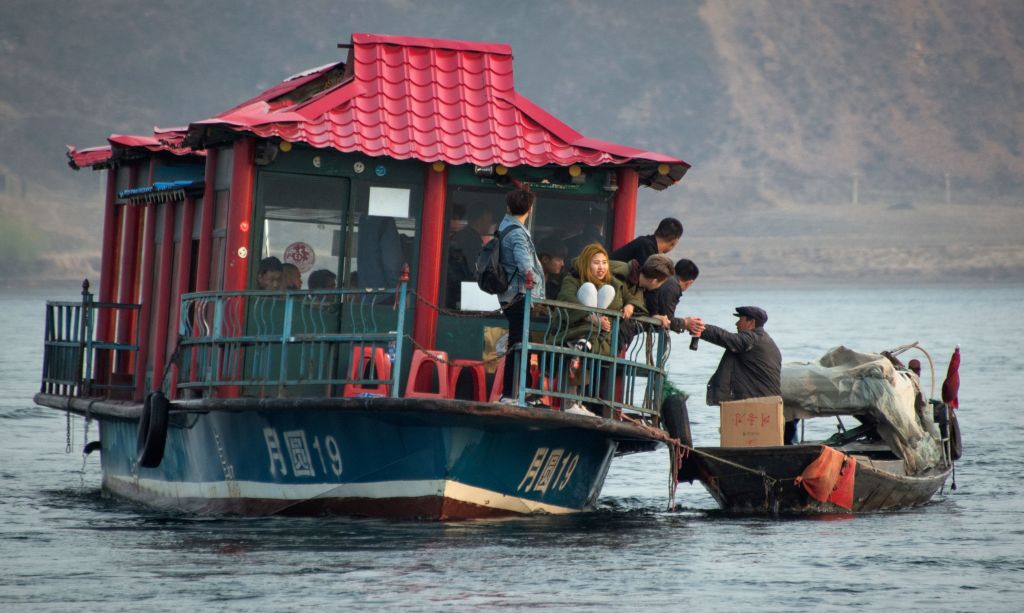 朝鲜男子(右)在鸭绿江沿岸向中国游客兜售朝鲜产品。(JOHANNES EISELE/AFP/Getty Images)