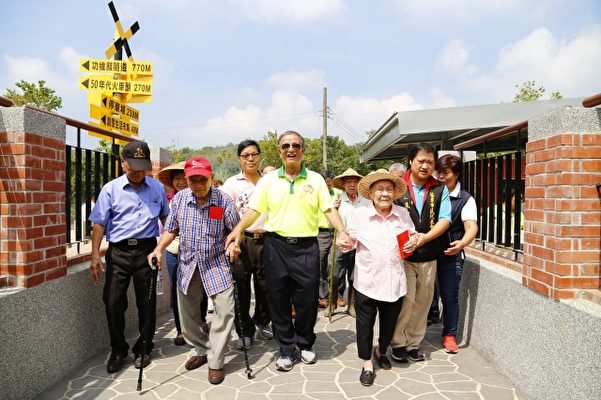 邱市长牵着百岁寿公寿婆，走过红砖尚禹桥，象征长久吉祥。（苗栗市公所提供）