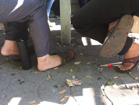 围聚打牌的华裔居民，脚边扔了很多烟头。