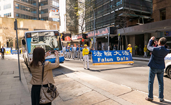 9月8日，法轮功学员的游行队伍经过悉尼市中心时，一些华人举起手机拍照。（冼楚棋／大纪元）