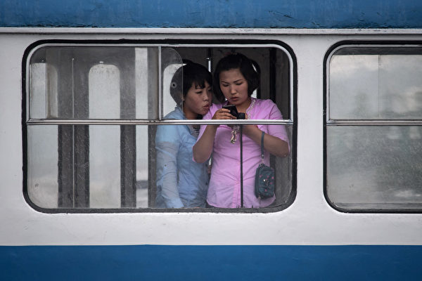 平壤一名女士在公交车上查看手机。(ED JONES/AFP/Getty Images)