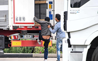 今年7月28日，企图偷渡者在光天化日下偷偷进入开往英国的货车。（ DENIS CHARLET/AFP/Getty Images)