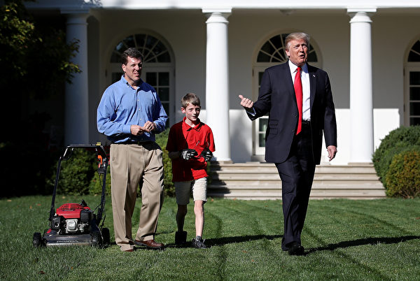 2017年9月15日上午，美国总统川普带着小弗兰克父子俩在白宫的玫瑰花园推草坪时，拍拍他的后背。(Win McNamee/Getty Images) 
