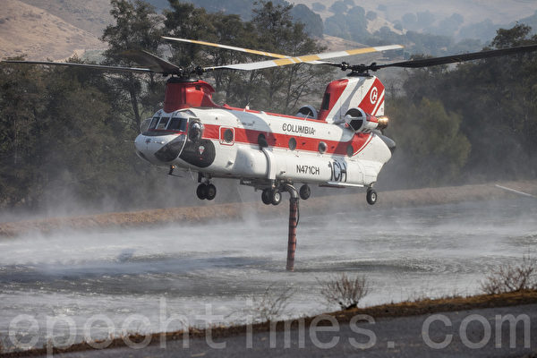 消防直升机在葡萄园的水塘里吸水后飞到火场灭火