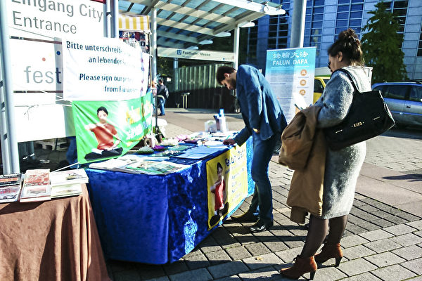 10月11日至15日法兰克福国际书展期间，法轮功学员在会展中心前讲真相。图为会展中心大门口与地铁口之间的摊位。（大纪元）