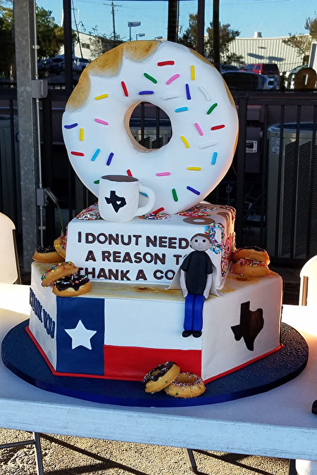 图：一家休斯顿糕点店为表示支持泰勒的善举，特别为当天制作了“甜甜圈男孩”主题的三层蛋糕。（易永琦／大纪元）