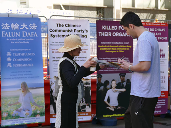 10月1日，全球退党中心悉尼分部在市中心的唐人街附近举行了声援“2亿8千5百万中国勇士退党”集会。图为澳洲民众在制止中共活摘法轮功学员器官请愿书上签名。（安平雅／大纪元）