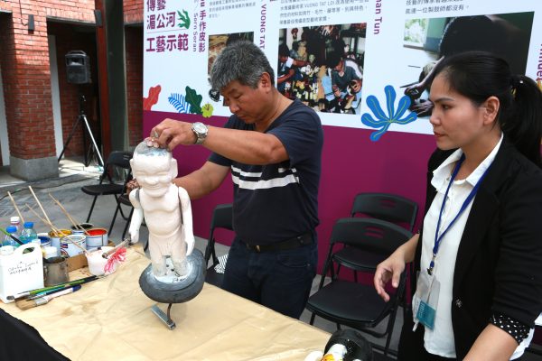 越南工艺师王必利的水傀儡是用无花果树雕刻而成，他正在用自然的油漆刷水傀儡。（曾汉东／大纪元）