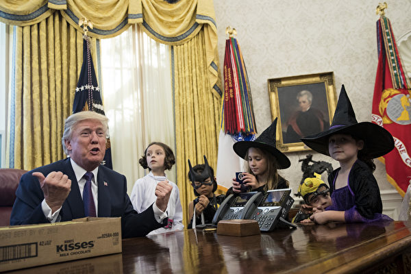 10月31日是萬聖節，27日，美國總統川普（特朗普）在白宮橢圓辦公室招待新聞記者的孩子們，並給孩子們發糖。(Drew Angerer/Getty Images)