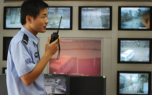 圖為2009年7月12日，安徽省合肥近郊一名警察在使用對講機，其背後是路燈監控攝像機返回的鏡頭。中國每年出現數以萬計的民眾抗議事件，比較常見的原因是政府腐敗和官方濫用權力。 (AFP/AFP/Getty Images)