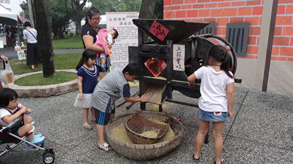 民眾在農具體驗區操作傳統的稻米打榖機。（曾晏均／大紀元）