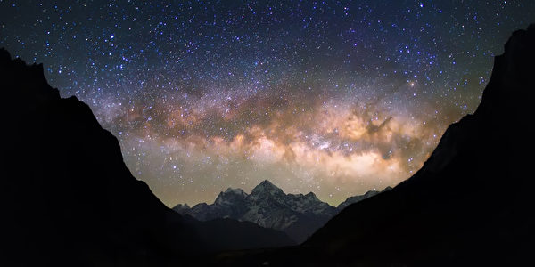 在多雪的山的明亮和生动的银河星系。 美丽的繁星满天的夜空似乎是在一个“碗”之间的映衬的山丘。